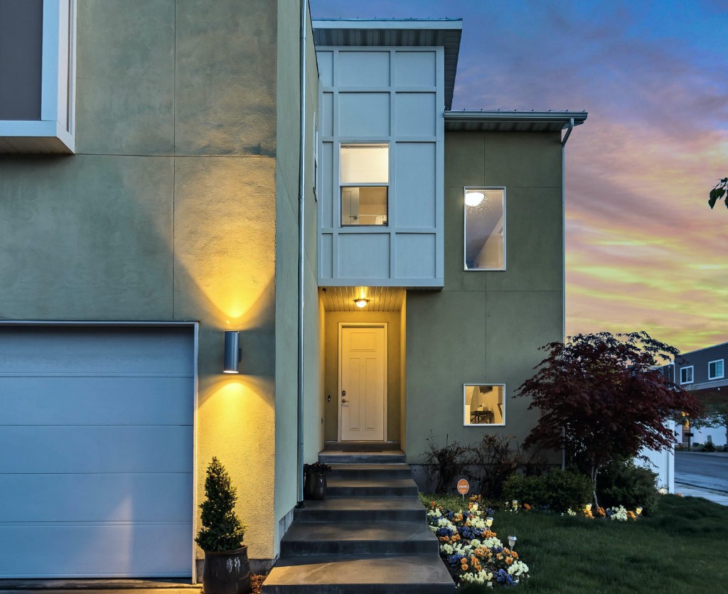 Fachada residencial al atardecer: entrada principal, garaje e iluminación exterior